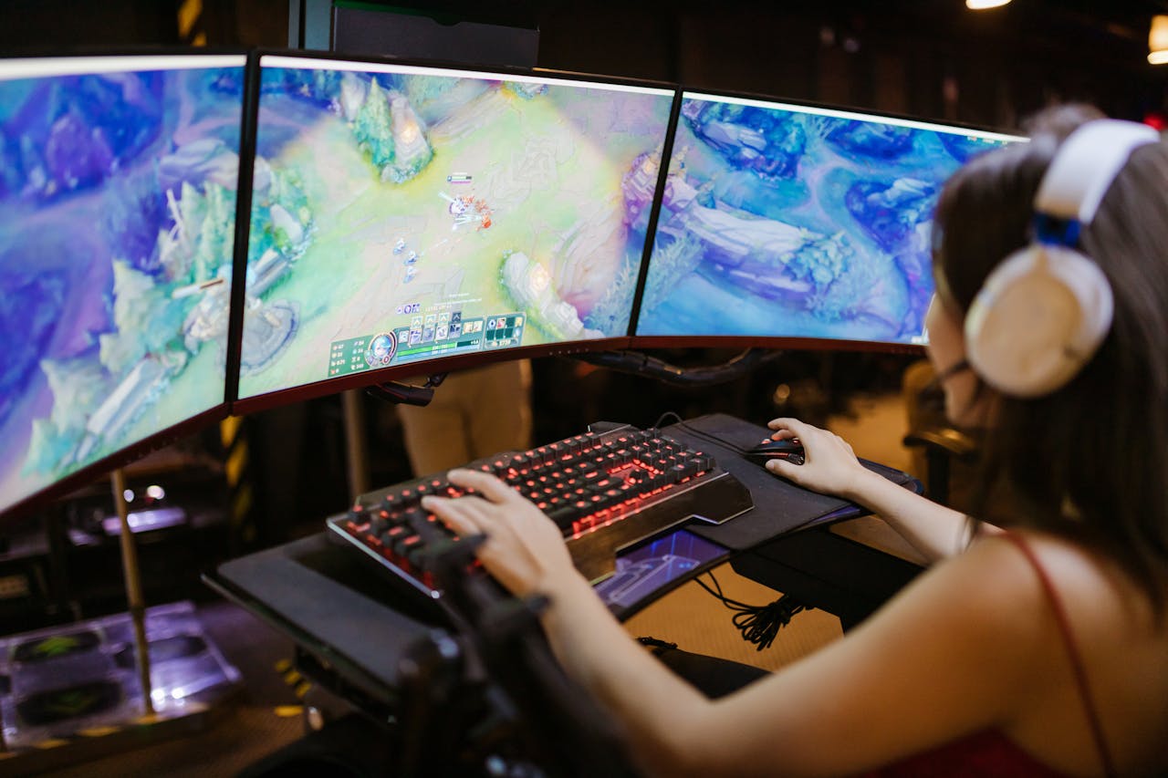 journey A young woman intently gaming on a multi-screen setup, showcasing vibrant gaming visuals.